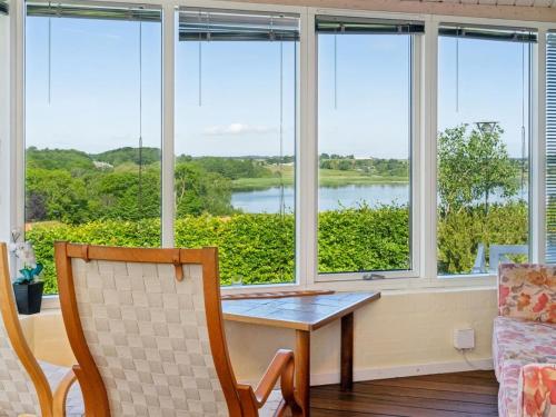 a living room with a table and chairs and windows at Holiday Home Eleana - 300m to the fjord by Interhome in Roskilde