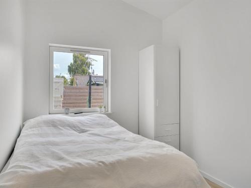 a white bedroom with a bed and a window at Holiday Home Fentje - 375m to the inlet by Interhome in Grevinge