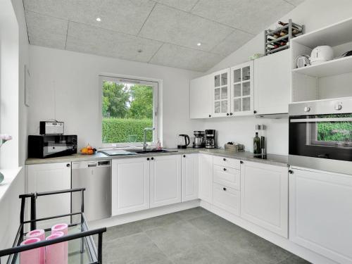 a white kitchen with white cabinets and a window at Holiday Home Fentje - 375m to the inlet by Interhome in Grevinge