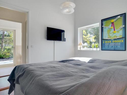 a bedroom with a bed and a tv on the wall at Holiday Home Rikkie - 150m to the fjord by Interhome in Rørvig