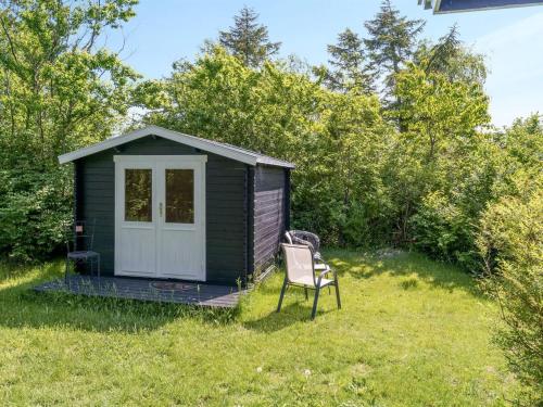 a small black shed with a chair in the grass at Holiday Home Gærmund - 350m from the sea by Interhome in Føllenslev