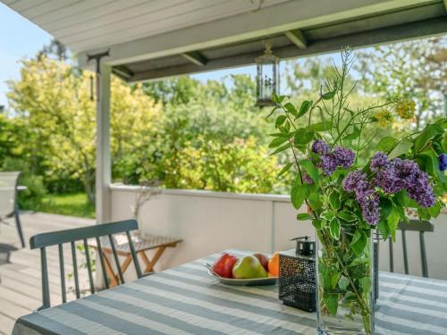 a vase of purple flowers on a table with a bowl of fruit at Holiday Home Gærmund - 350m from the sea by Interhome in Føllenslev