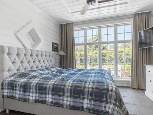 a bedroom with a bed with a plaid blanket at Holiday Home Titia - 1-2km to the inlet by Interhome in Rørvig