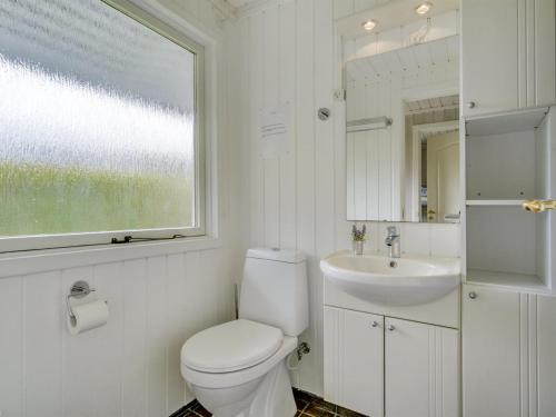 a white bathroom with a toilet and a sink at Holiday Home Erva - 495m from the sea by Interhome in Gedser