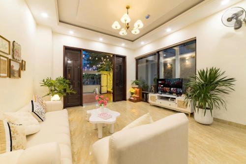 Una sala de estar con muebles blancos y un televisor de pantalla plana. en Danang's house, en Da Nang