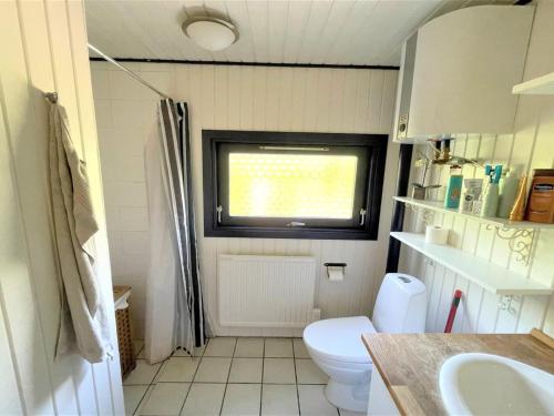 a small bathroom with a toilet and a window at Holiday Home Maiken - 1-5km from the sea by Interhome in Føllenslev