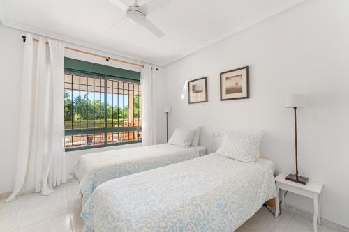 zwei Betten in einem weißen Zimmer mit Fenster in der Unterkunft Casa Ra Sol in Orihuela
