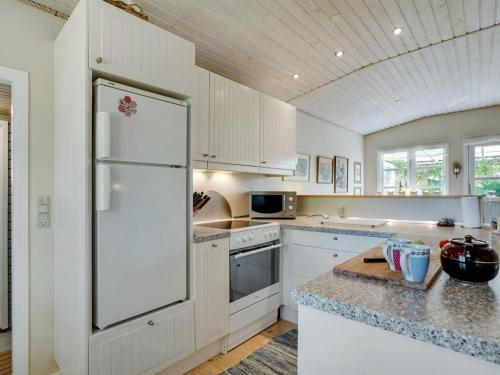 a kitchen with white cabinets and a refrigerator at Holiday Home Haldis - 120m from the sea by Interhome in Stubbekøbing