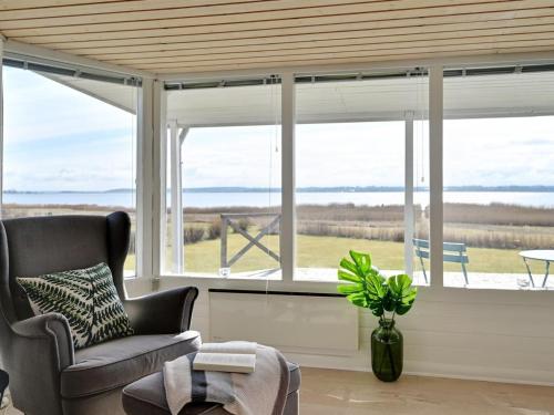 a living room with a chair and a large window at Holiday Home Caren - 125m to the inlet by Interhome in Holbæk