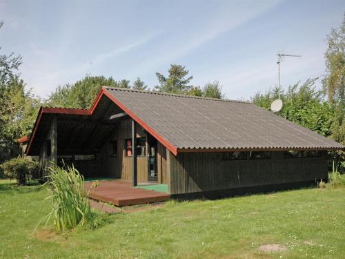 a small house with a black roof in a field at Holiday Home Spasena - 400m from the sea by Interhome in Gedser
