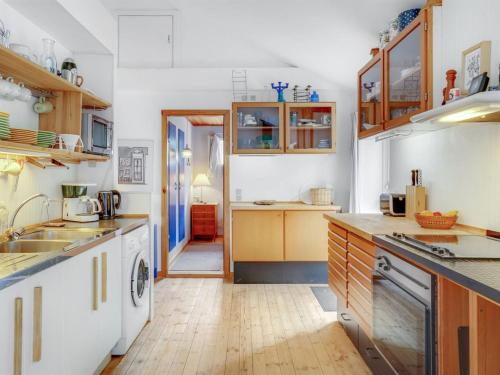 a kitchen with white cabinets and a wooden floor at Holiday Home Carmen - 25m from the sea by Interhome in Lumsås