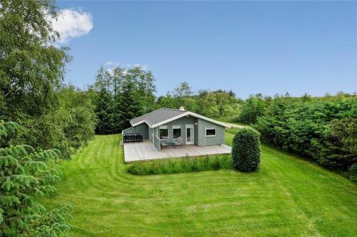a small green cabin in a field with a yard at JB122-Fjerritslev-Tyttebaerstien-14 in Torup Strand