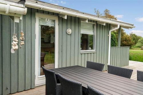 a green house with a table and chairs on a deck at JB122-Fjerritslev-Tyttebaerstien-14 in Torup Strand