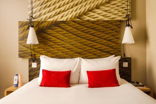 a bed with two red pillows in a room at ibis London Canning Town in London