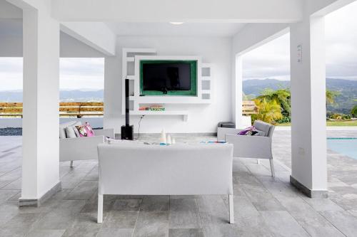 a living room with white furniture and a tv at Home for 10 with Pool and Solar Panels in Caguas! in Caguas