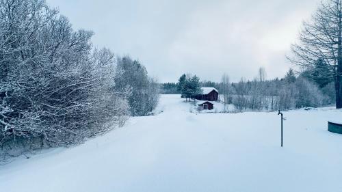 a snow covered field with a barn in the distance at Cozy Family Villa for aurora lovers in Byske