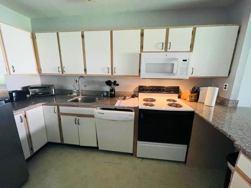 a kitchen with white cabinets and a stove and microwave at Spacious 2br2ba Firstfloor Condo in Jenkintown
