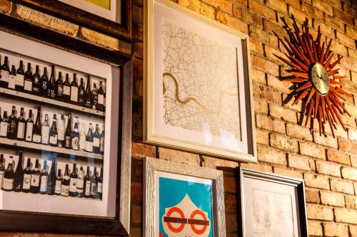 a brick wall with framed pictures and a clock at ibis London Canning Town in London