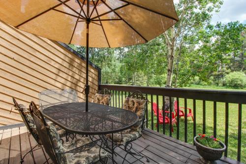 a table and chairs on a deck with an umbrella at Meadow Creek in Frisco