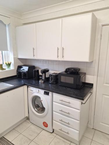 a kitchen with a washing machine and a microwave at Florina house in Little Hulton