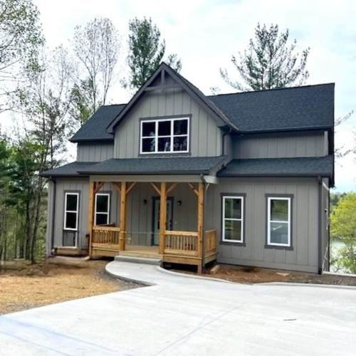 a tiny house with a porch and a gambrel roof at The Overlook at Lake James in Nebo