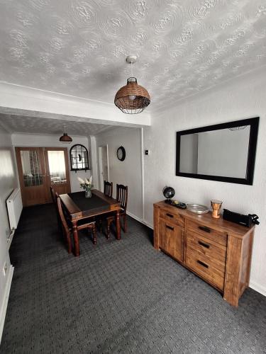 a dining room with a table and a flat screen tv at Florina house in Little Hulton