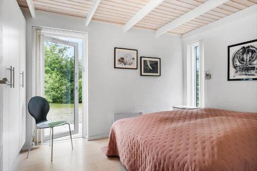a bedroom with a bed and a chair and a window at JB178-Brovst-Kronvildtvej-3 in Tranum