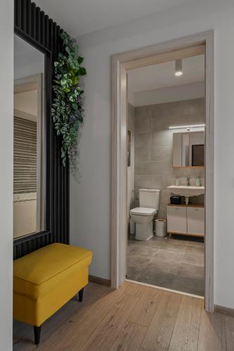 a bathroom with a toilet and a yellow ottoman at Garsoniera Turquoise Rezidential Moghioros Park in Bucharest