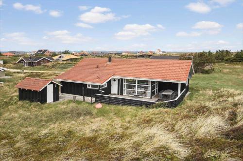 a house with an orange roof in a field at JB705-Frostrup-Svenstibakkevej-82 in Lild Strand