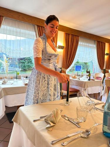 a woman is standing over a table in a restaurant at Hotel Vigo in Vigo di Fassa