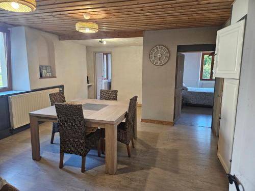 Una mesa de comedor con sillas y un reloj en la pared. en Le moulinot, en Morteau