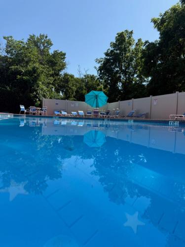 a swimming pool with chairs and an umbrella at Beautiful, Spacious, 22 In Elkins Park in Jenkintown