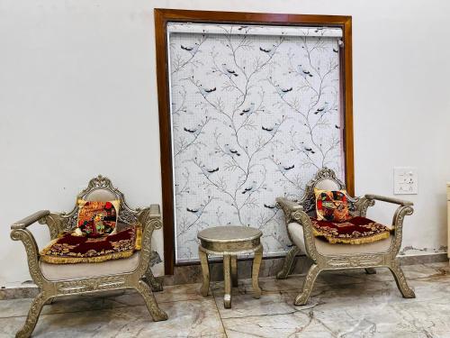 two chairs and a table in front of a wall at Gift city farmhouse in Gandhinagar