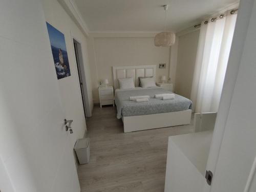 a white bedroom with a bed and a bathroom at Brisa do Mar 2 - Consolação in Peniche