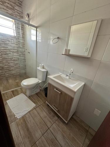 a white bathroom with a toilet and a sink at Hotel e Restaurante Santa Fé in Lages