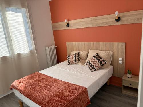 a bedroom with orange walls and a bed with pillows at Central Hôtel in Saint-Priest