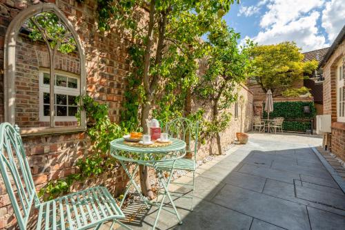 a patio with a table and chairs next to a brick wall at Moatside Gate in York