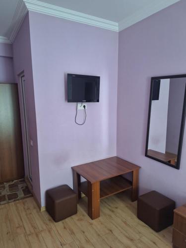 a room with a table and a tv on a wall at Hotel Nina in Tbilisi City