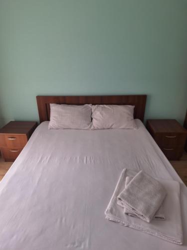 a bed with a white blanket and a towel on it at Hotel Nina in Tbilisi City
