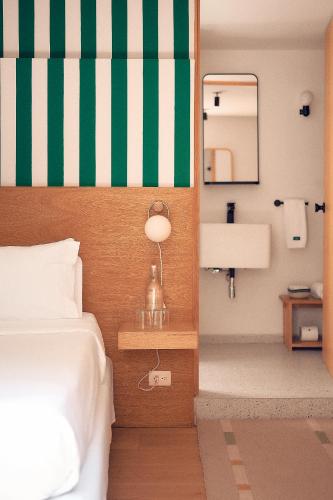 a bedroom with a bed with a green and white striped wall at Hotel Parián in Mexico City