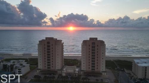 a sunset over the ocean with two tall buildings at Island Time #4 condo in South Padre Island