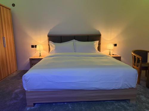 a bedroom with a large white bed with two lamps at شقق دفادف المخدومة in Hail