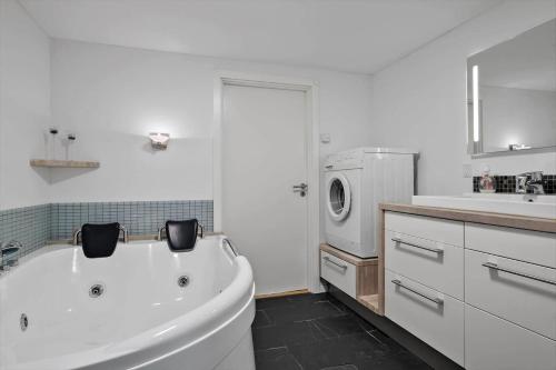 a white bathroom with a tub and a washing machine at JB908-Brovst-Kronvildtvej-190 in Tranum