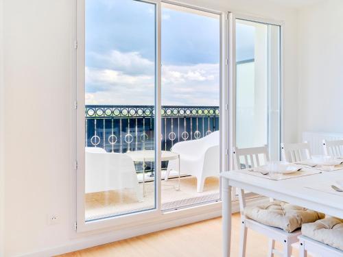 a white dining room with a view of the ocean at Parisian Haven - Chic Penthouse near Paris & CDG in Le Blanc-Mesnil