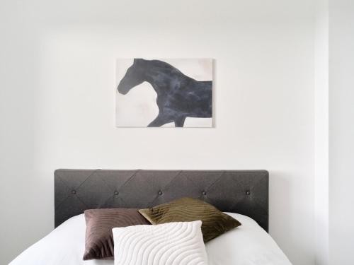 a black horse picture on the wall above a bed at Parisian Haven - Chic Penthouse near Paris & CDG in Le Blanc-Mesnil