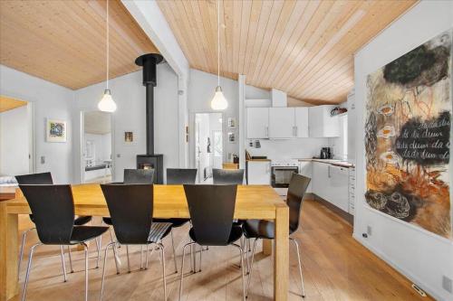 a dining room and kitchen with a wooden table and chairs at JB167-Fjerritslev-Revlingestien-83 in Torup Strand