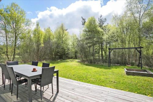 a table and chairs on a wooden deck with a garden at JB167-Fjerritslev-Revlingestien-83 in Torup Strand