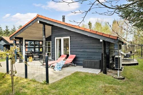 a small cabin with two chairs on a deck at JB314-Fjerritslev-Tyttebaerstien-13 in Torup Strand