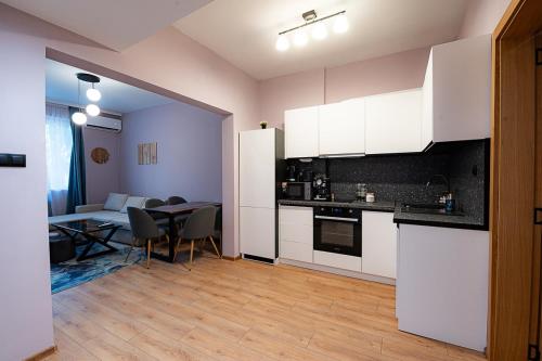 a kitchen with white cabinets and a table and a living room at 1 minute to main Street & NDK & Free Parking in Sofia