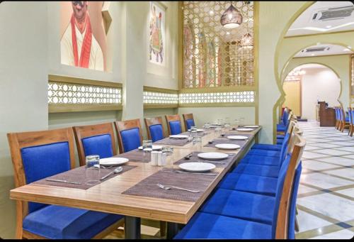 a dining room with a long table and blue chairs at Hotel Dev Sagar & Restaurant in Agra